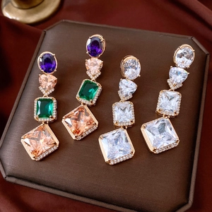 Macro detail of vintage geometric tassel earrings with colorful zircons and gold plating
