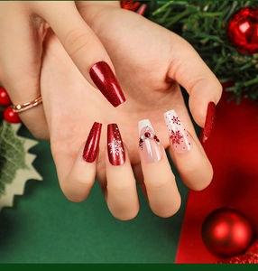 Macro detail of Christmas coffin press-on nails with red glitter and snowflake designs