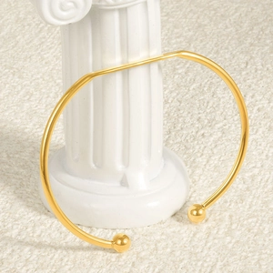 Minimalist 18k gold plated stainless steel open bangle with spherical ends on white fur