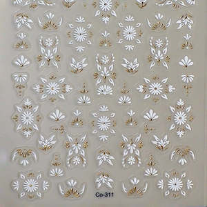 3D embossed nail decals with white and gold floral motifs on transparent sheet