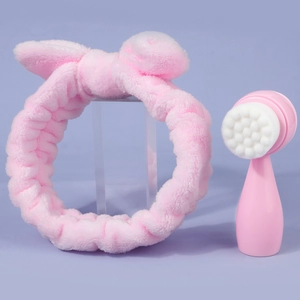 Pink bow headband and soft bristle silicone facial cleansing brush set on purple background
