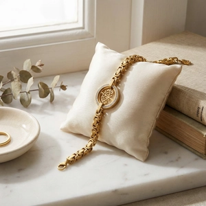 Détail du bracelet doré Arbre de Vie sur coussin en soie avec fond en marbre chic