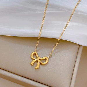 Detail of a gold bow pendant necklace on white silk fabric and beige jewelry box