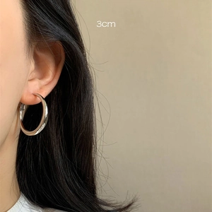 Close-up of 3cm silver hoop earring worn on ear showing polished metallic luster