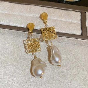 Macro shot of gold hollow anagram earrings with high-quality baroque pearls on display