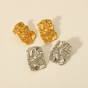 Detailed view of lava-style textured gold and silver earrings with irregular folds