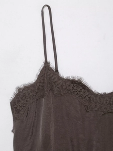 Macro detail of dark brown lace trim on silky satin camisole top with elegant stitching