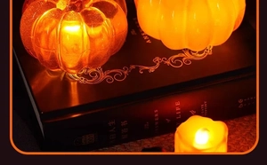 Close-up of orange LED pumpkin candle light with warm glow on decorative books