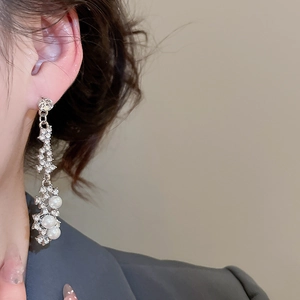 Close-up of elegant silver drop earrings with shimmering pearls and rhinestones on a model