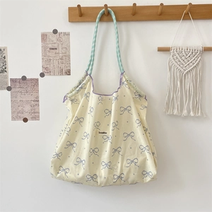 Detail of canvas tote bag featuring purple piping and checkered ribbon drawstring handles