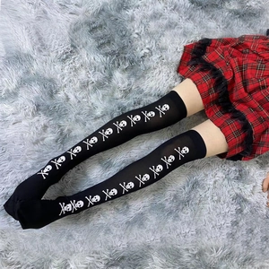 Close-up of black over-knee socks with white skull print against a plush carpet