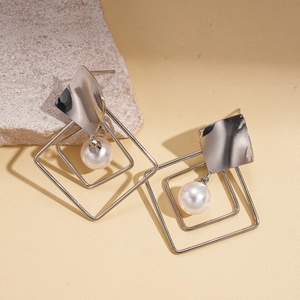 Close-up of geometric silver earrings with layered square frames and a white pearl drop