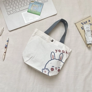 Detail of white canvas tote featuring cute rabbit print and secure metal snap closure