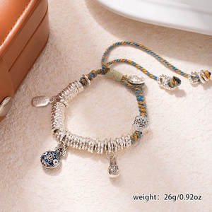 Macro detail of hand-woven bracelet with silver pendants and enamel charms