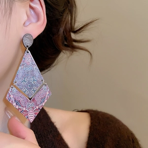 Detail of bohemian geometric wood pendant earring featuring ethnic patterns on a model