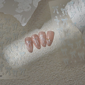 Detail von 3D weißen Schleifen- und Stern-Nagelstickern mit irisierendem Perlmutt-Finish