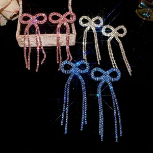 Bow tassel drop earrings set with crystals in pink, silver, and blue on black velvet