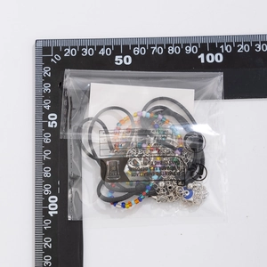 Detail of beaded turquoise necklace set and tree of life charms on measurement scale