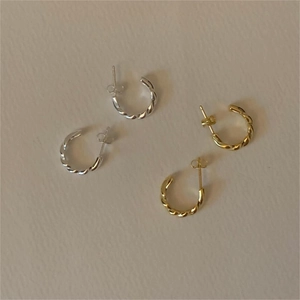 Macro shot of twisted rope design earrings in silver and gold finishes with metal backings
