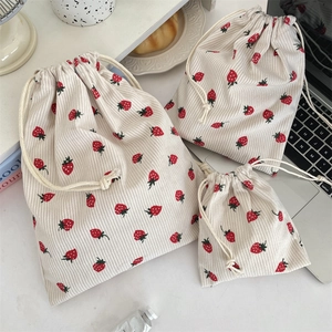 Detailed texture of beige corduroy drawstring bags with red strawberry print pattern