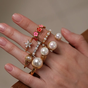 Detailed view of layered 18K gold plated flower rings with pearls and zircon on model hand