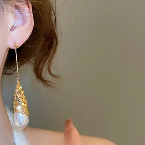 Detail of elegant 18k gold plated long drop earring with large teardrop pearl on a model