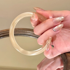 Dettaglio macro del bracciale circolare in vetro ambrato con finitura lucida