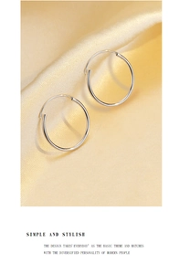 Detail of silver round hoop earrings resting on elegant light gold silk fabric