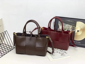 Detailed view of dark brown and wine red woven leather tote bags with wide weave texture