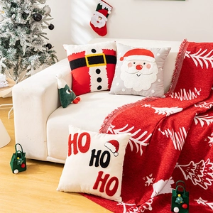 Detailed Christmas pillow covers with Santa motifs and festive red throw blanket on sofa