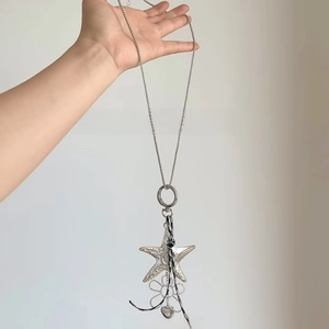 Detail of silver long chain bohemian star and flower pendant with textured finish