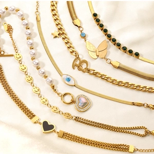 Close-up of golden bracelets with pearl, heart charms and emerald green gemstones