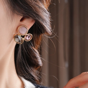 Close-up of vintage oval earrings with cat eye stones and faceted gems on golden metal