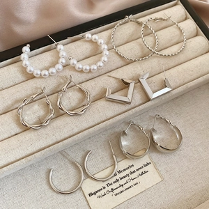 Close-up of geometric silver pearl earring set displayed in a beige jewelry box