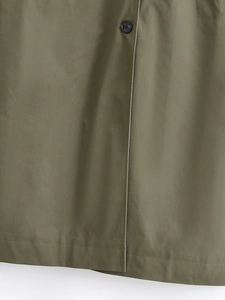 Close-up of army green trench coat fabric texture with black button and stitched hem