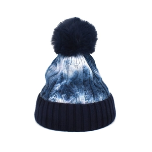 Winter tie-dye knit beanie with blue pompom and thick cable texture for warmth