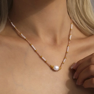 Elegante collana di perle bianche e cristalli rosa sul collo di una modella