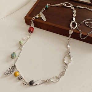 Detail of vintage ethnic long necklace with colorful ceramic beads and leaf pendants