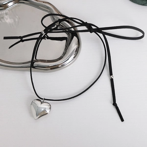 Minimalist heart pendant necklace with black cord cord on a sleek silver tray