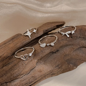 Macro shot of S925 sterling silver bow and star rings with zircon inlay on wood