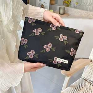 Detail of black fabric pouch with pink floral embroidery and May Rabbit label