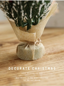 Close-up of a mini Christmas tree base wrapped in rustic burlap on a wooden table