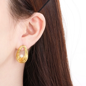Close-up of elegant gold layered spiral earrings with white pearl on a model's ear