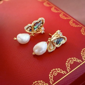 Macro detail of golden butterfly earring with iridescent shell and baroque pearl inlay