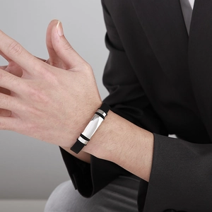 Close-up of men's black silicone leather bracelet with polished silver metal nameplate