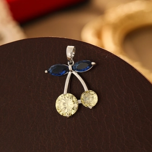 Macro shot of silver cherry pendant with blue and yellow gemstone inlay on leather