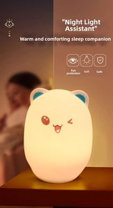 Macro shot of bear-shaped silicone night light with warm orange glow on a wooden surface