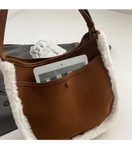 Close-up of brown suede underarm bag with plush trim showing large front pocket for tablet