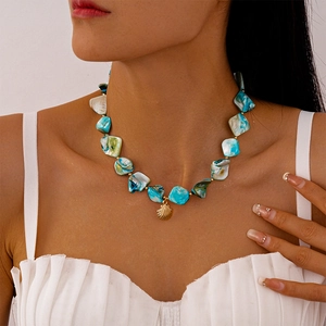 Dettaglio della collana in pietre blu con ciondolo a conchiglia dorata su una modella