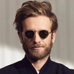 Fashionable round retro sunglasses with gold metal frames and tea lenses on a model